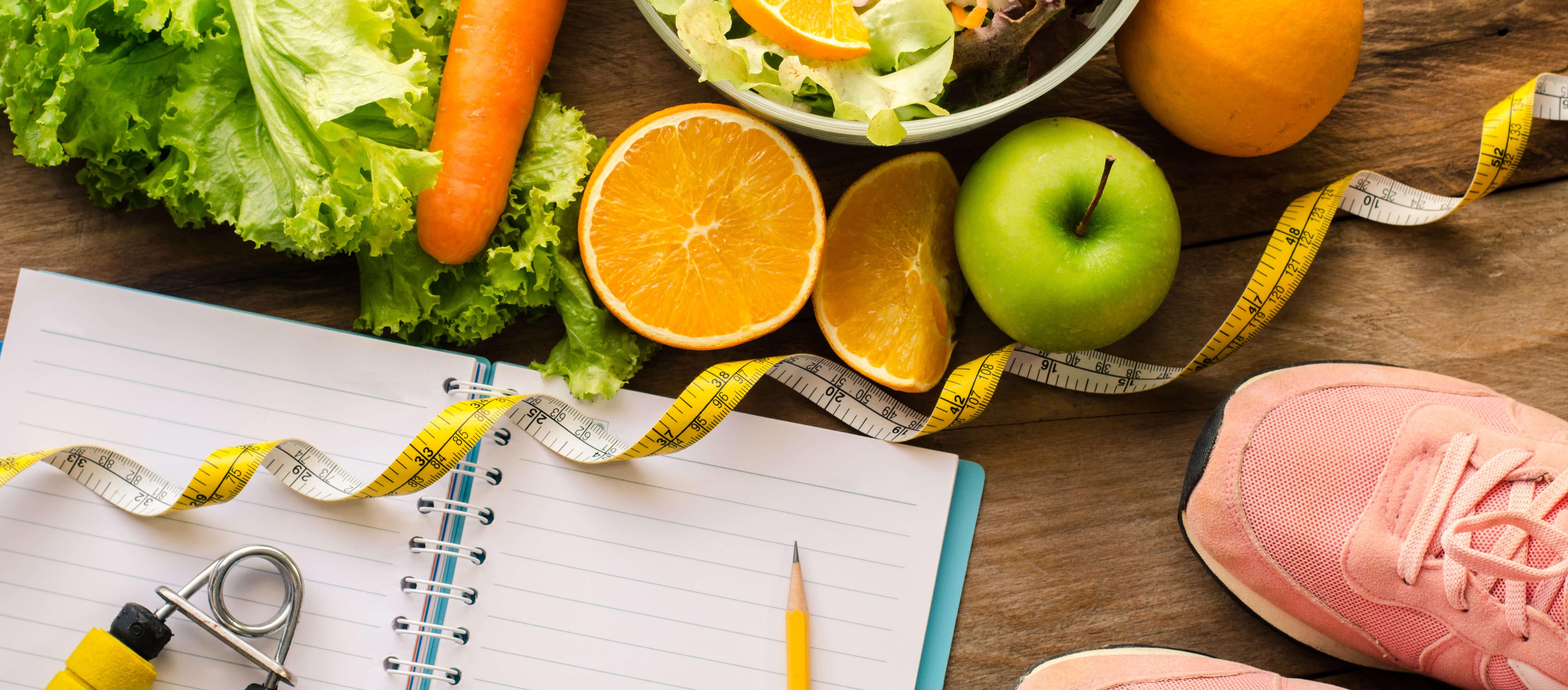 Obst, Gemüse, Laufschuhe, Maßband und Block mit Stift
